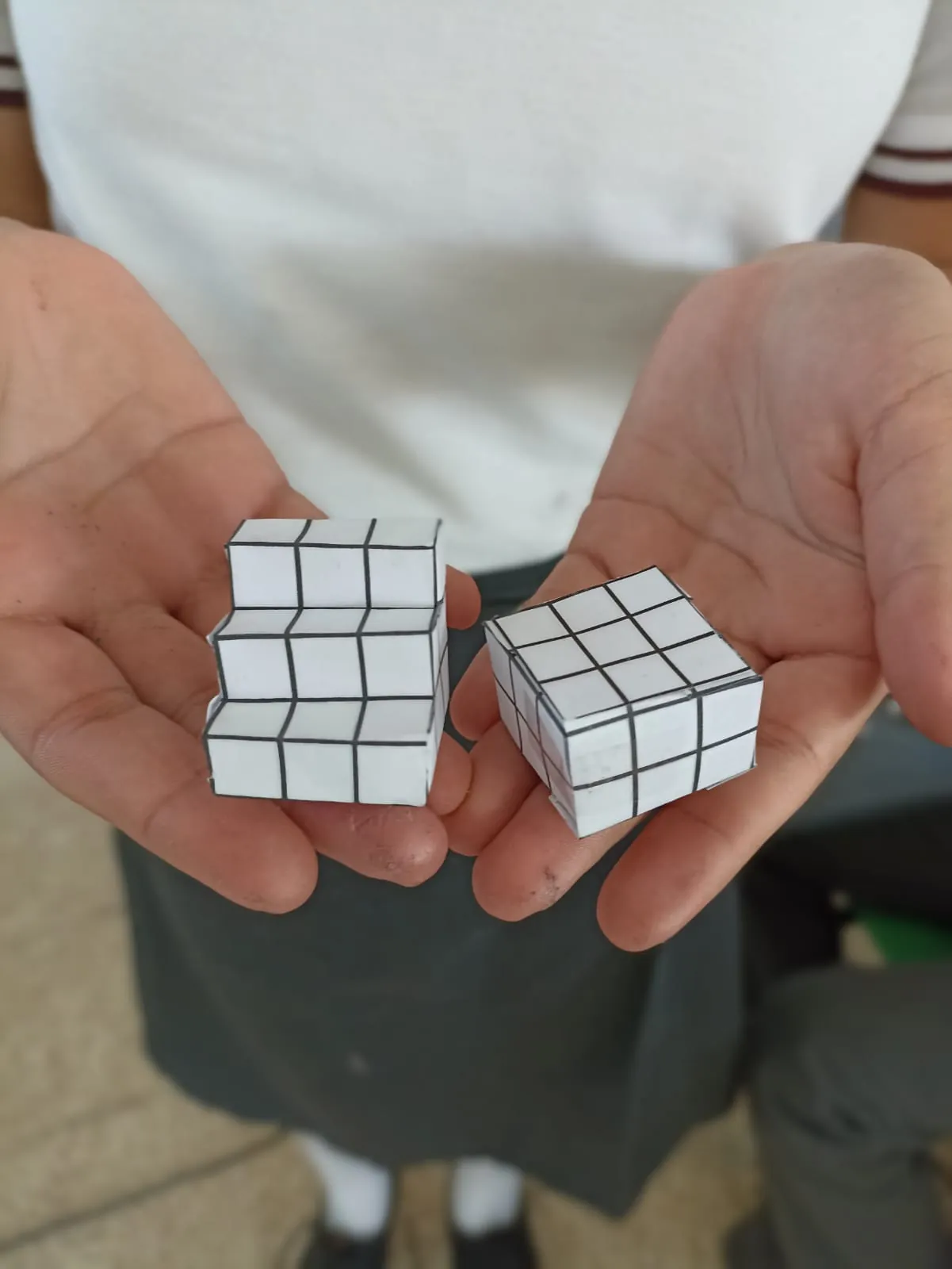Dos cubos de papel armados, uno en cada mano