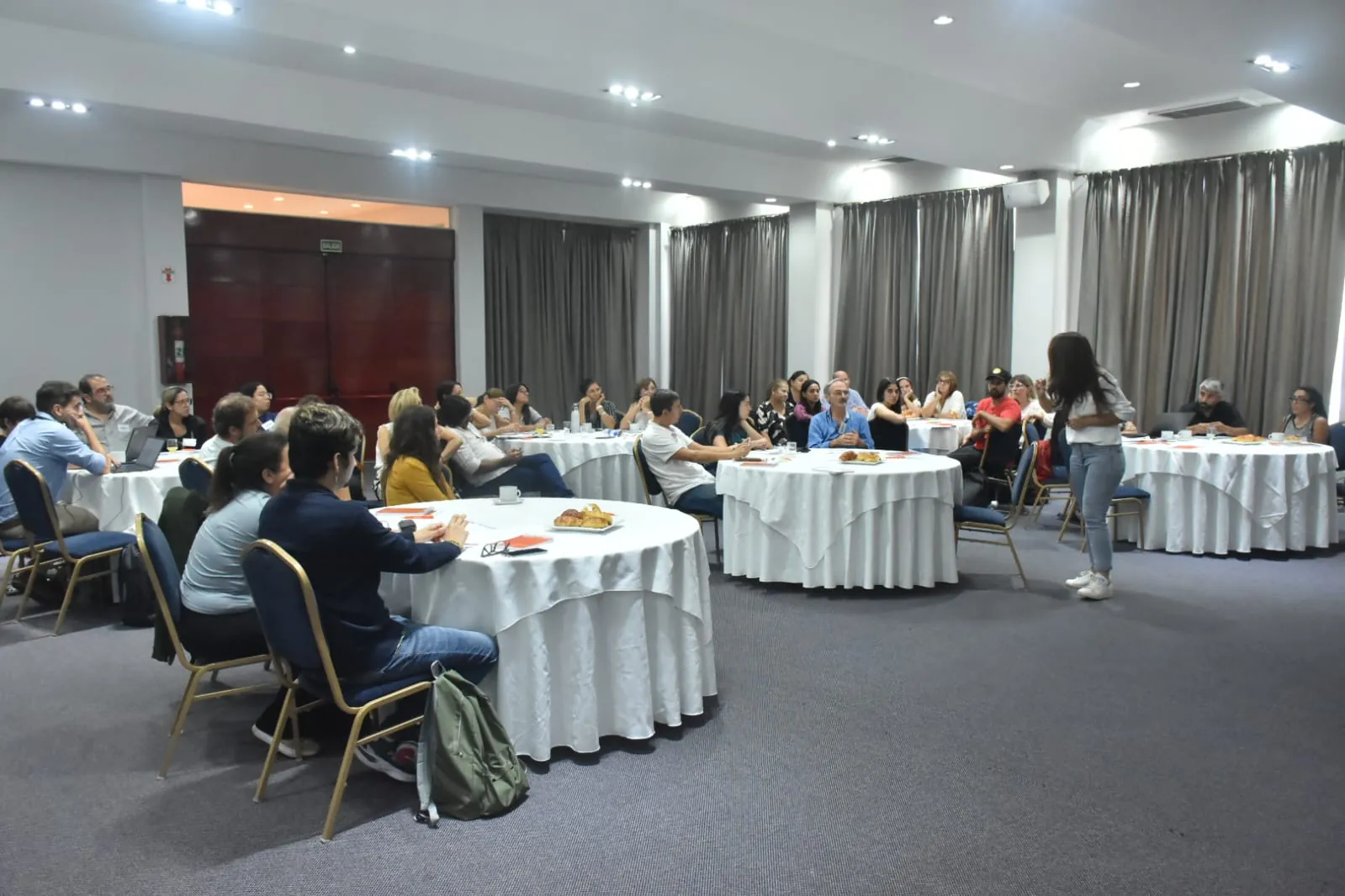 Docentes trabajan en mesas redondas en un salón de encuentros